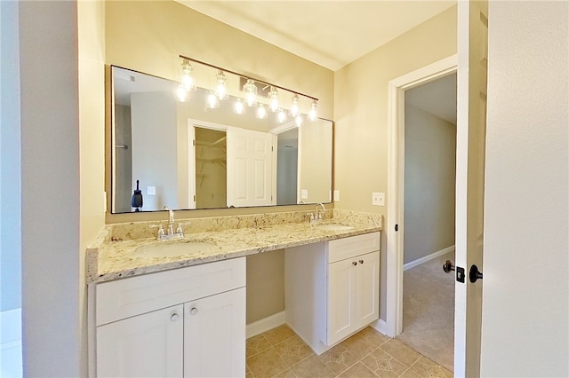 bathroom with a sink, tile patterned floors, baseboards, and double vanity