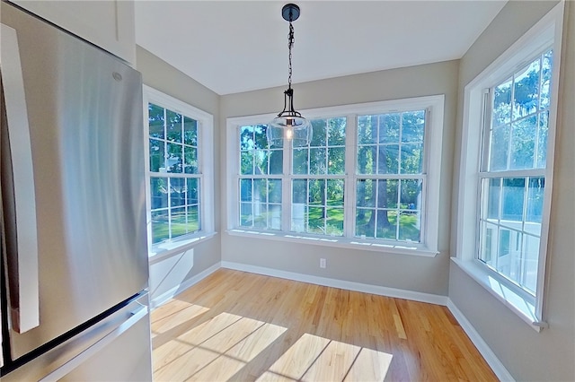 unfurnished dining area with light wood-style floors, baseboards, and a healthy amount of sunlight