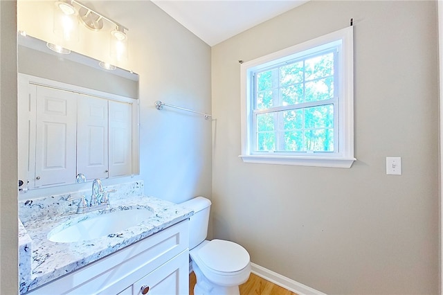 bathroom featuring toilet, baseboards, wood finished floors, and vanity