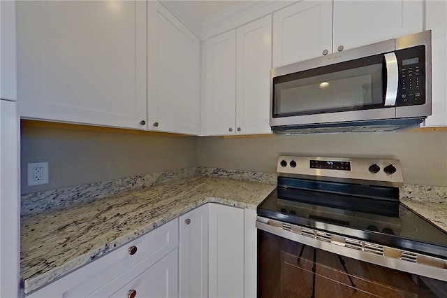 kitchen featuring appliances with stainless steel finishes, white cabinets, and light stone counters