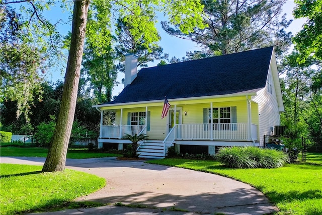 view of front facade with a chimney, a porch, and a front lawn