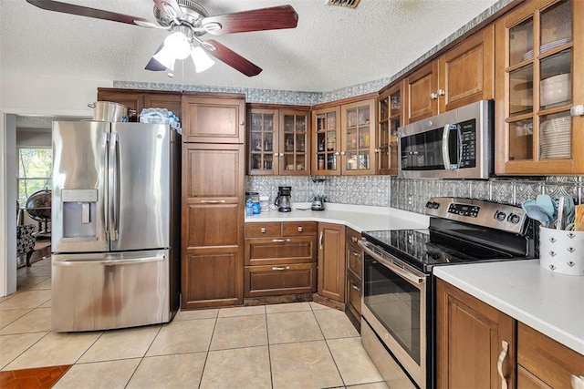 kitchen with ceiling fan, light tile patterned flooring, a textured ceiling, and appliances with stainless steel finishes