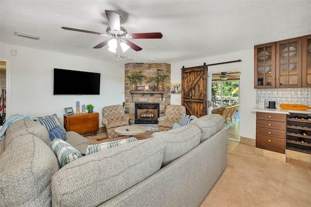 carpeted living room with a fireplace, a barn door, a textured ceiling, and ceiling fan