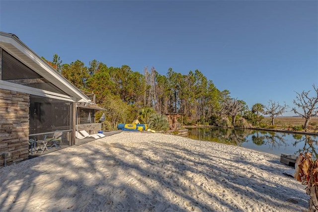 view of yard with a sunroom and a water view