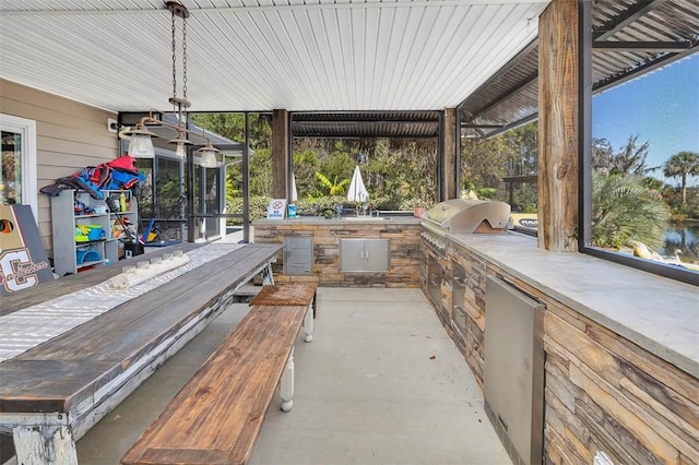 view of patio / terrace featuring a grill, a sunroom, and exterior kitchen