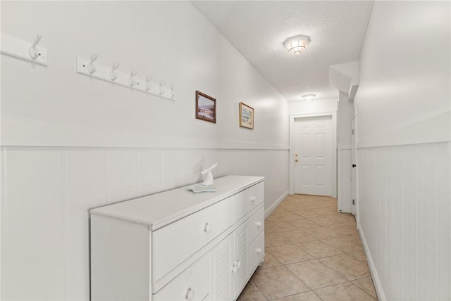 hallway with a textured ceiling and light tile patterned floors