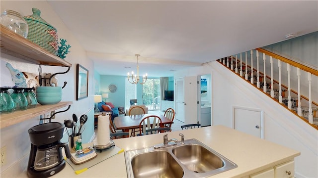 kitchen featuring white cabinets, an inviting chandelier, hanging light fixtures, and sink