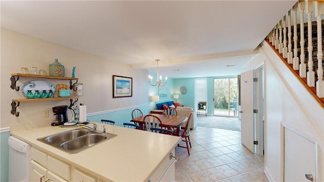 kitchen featuring dishwasher, sink, hanging light fixtures, an inviting chandelier, and light tile patterned flooring