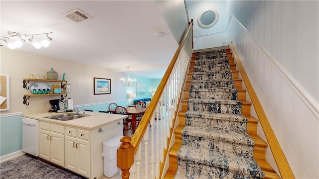 stairway with hardwood / wood-style floors, sink, and a chandelier