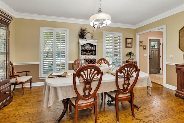 dining room featuring wood finished floors, crown molding, and baseboards
