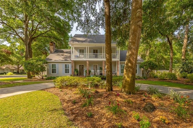 view of front of property featuring covered porch, a balcony, and a chimney
