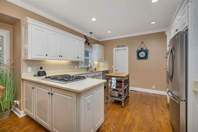 kitchen featuring appliances with stainless steel finishes, a sink, white cabinets, light countertops, and wood finished floors