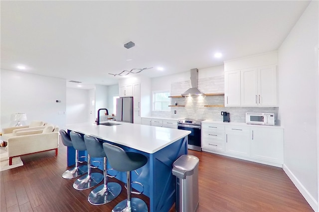 3935 Memorial Dr, Waycross, GA 31503 - kitchen with stainless steel appliances, dark wood-style flooring, a sink, backsplash, and wall chimney exhaust hood