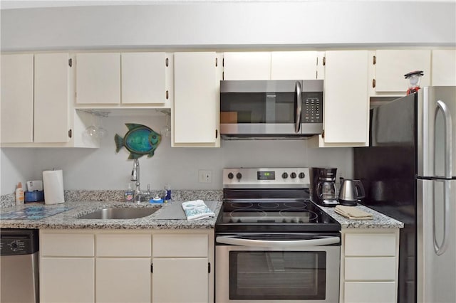 kitchen featuring stainless steel appliances, light stone countertops, sink, and white cabinets