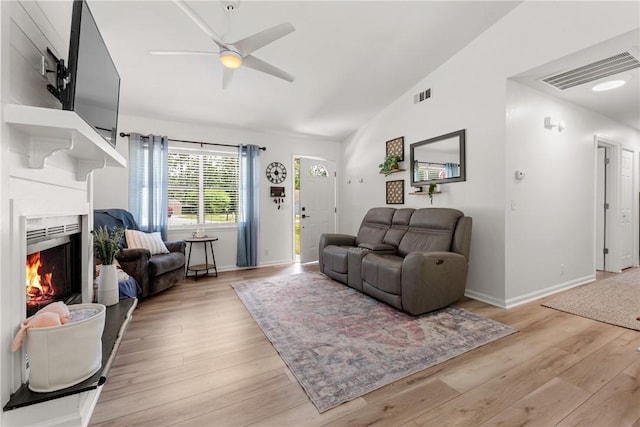 living area with visible vents, ceiling fan, vaulted ceiling, and light wood-type flooring