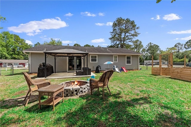 rear view of property featuring a patio area, a gazebo, a fenced backyard, an outdoor fire pit, and a yard