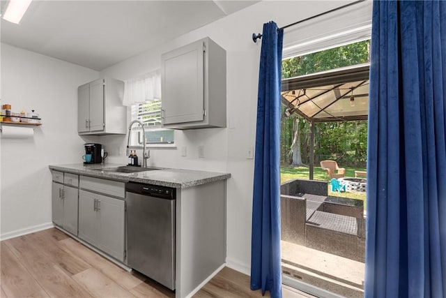 kitchen featuring a sink, stainless steel dishwasher, gray cabinetry, and light wood finished floors