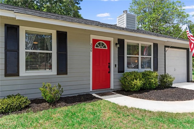 entrance to property with a garage, covered porch, and a chimney
