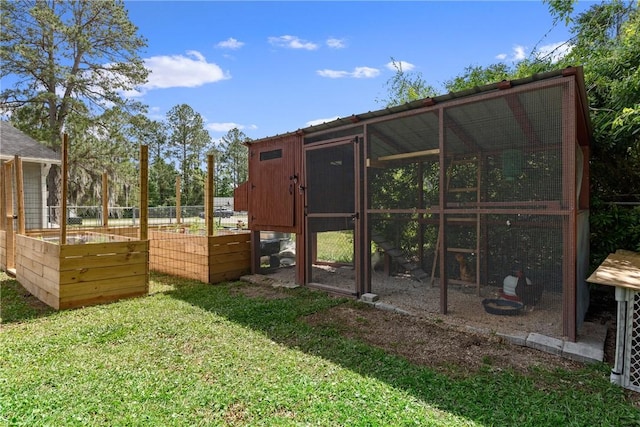 view of poultry coop featuring a lawn, fence, and a garden