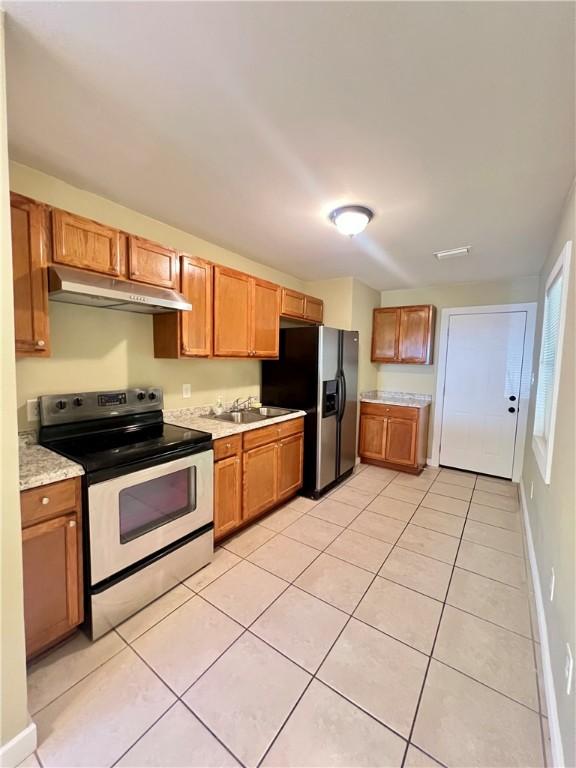 1920 Washington St, Brunswick, GA 31520 - kitchen with stainless steel range with electric stovetop, under cabinet range hood, refrigerator with ice dispenser, light countertops, and light tile patterned flooring