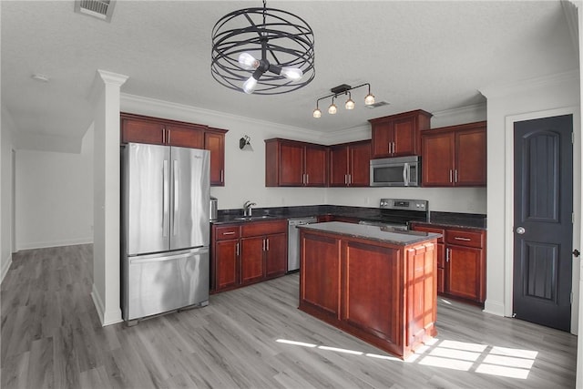 kitchen with appliances with stainless steel finishes, light hardwood / wood-style floors, a kitchen island, and sink