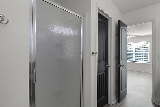 bathroom with ceiling fan and a shower with door