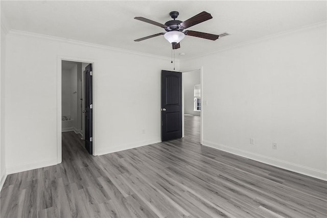 empty room featuring ceiling fan, crown molding, and dark wood-type flooring