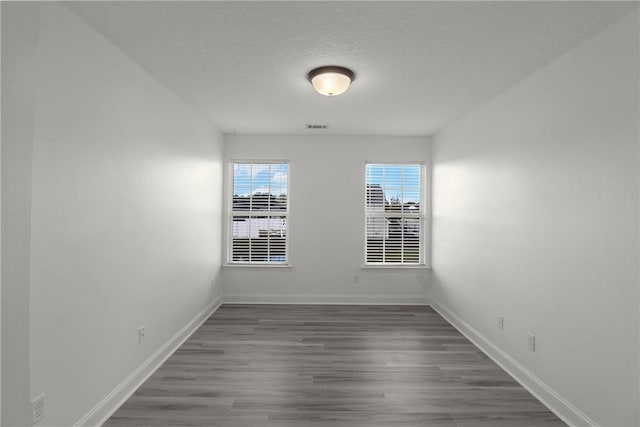 unfurnished room with dark hardwood / wood-style flooring and a textured ceiling