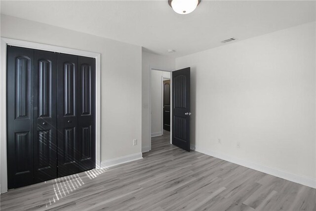 unfurnished bedroom featuring light wood-type flooring and a closet