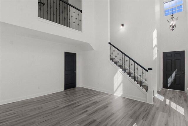 foyer entrance with a towering ceiling, hardwood / wood-style flooring, and a notable chandelier