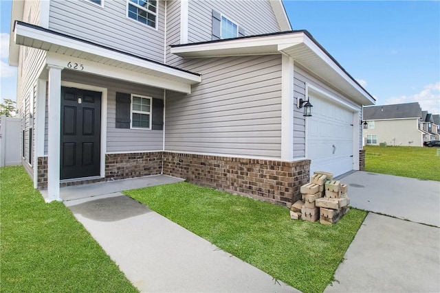 view of exterior entry with a lawn and a garage