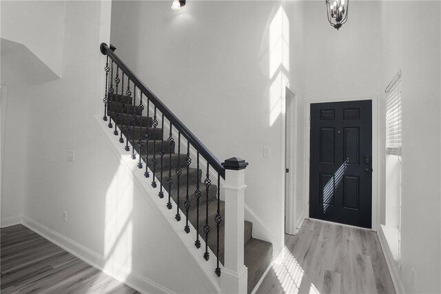 entryway with a chandelier, a towering ceiling, and wood-type flooring