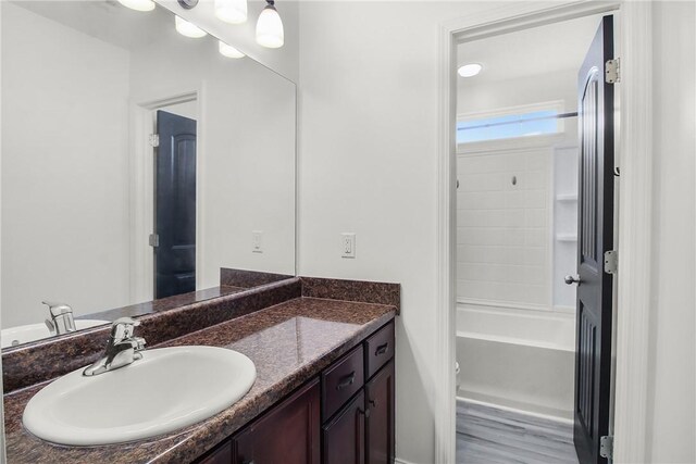 bathroom with wood-type flooring, vanity, and  shower combination