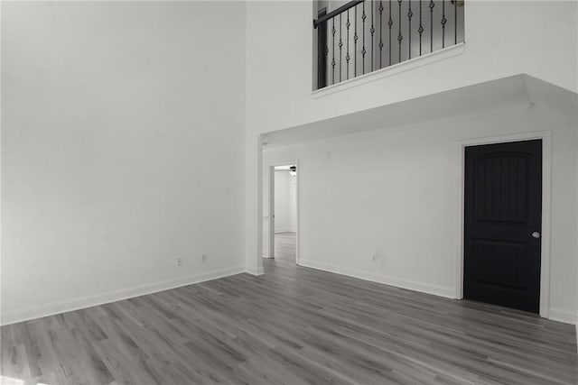 unfurnished living room featuring hardwood / wood-style floors and a towering ceiling