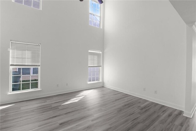 unfurnished living room featuring hardwood / wood-style floors and a towering ceiling