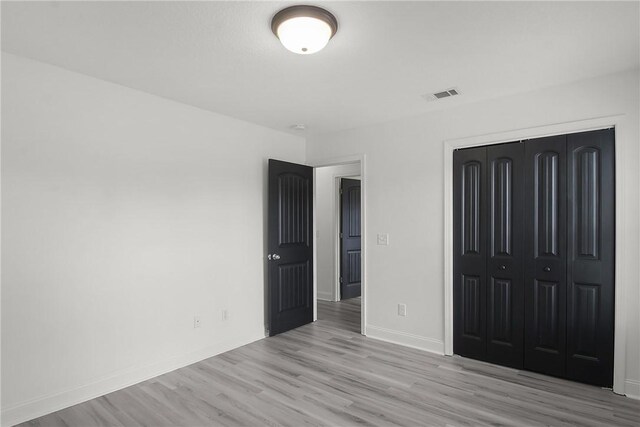 unfurnished bedroom featuring light hardwood / wood-style floors and a closet