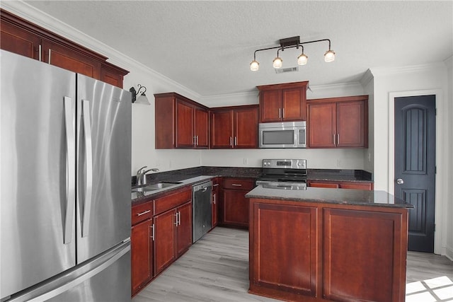 kitchen with sink, a center island, light wood-type flooring, and appliances with stainless steel finishes