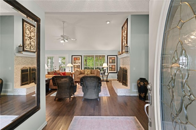 living room featuring hardwood / wood-style flooring, ceiling fan, lofted ceiling, and a textured ceiling