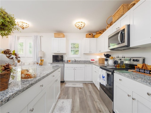138 Mohr Club Dr, Darien, GA 31305 - kitchen featuring stainless steel appliances, light wood-style flooring, white cabinets, light stone counters, and a sink