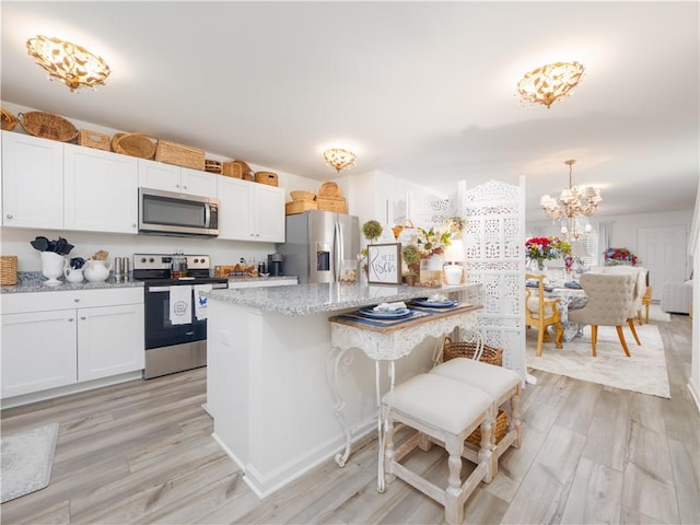 138 Mohr Club Dr, Darien, GA 31305 - kitchen with appliances with stainless steel finishes, a center island, a chandelier, light stone countertops, and light wood-style floors