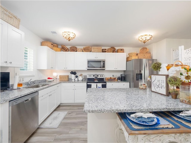 138 Mohr Club Dr, Darien, GA 31305 - kitchen featuring appliances with stainless steel finishes, a sink, white cabinets, and light stone countertops