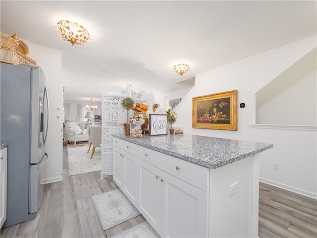 138 Mohr Club Dr, Darien, GA 31305 - kitchen featuring freestanding refrigerator, a chandelier, light wood-style floors, white cabinetry, and light stone counters