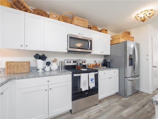 138 Mohr Club Dr, Darien, GA 31305 - kitchen featuring stainless steel appliances, light wood finished floors, white cabinetry, and light stone countertops