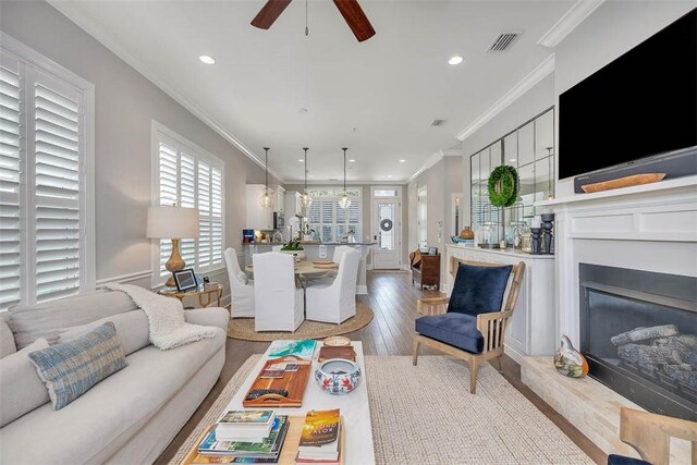 living room featuring ceiling fan, light hardwood / wood-style floors, and ornamental molding