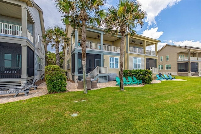 back of house with a balcony, ceiling fan, and a lawn