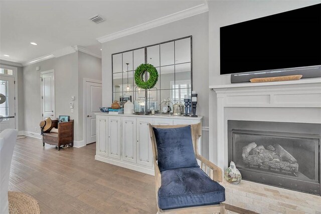 interior space featuring a brick fireplace, light hardwood / wood-style flooring, and ornamental molding