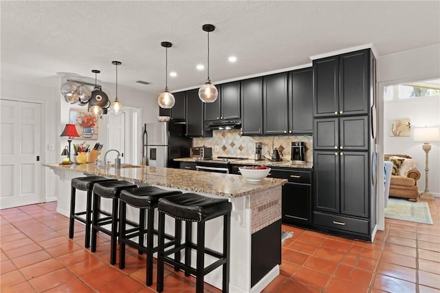 105 Driftwood Pl, Saint Simons Island, GA 31522 - kitchen featuring appliances with stainless steel finishes, decorative backsplash, under cabinet range hood, a kitchen bar, and recessed lighting