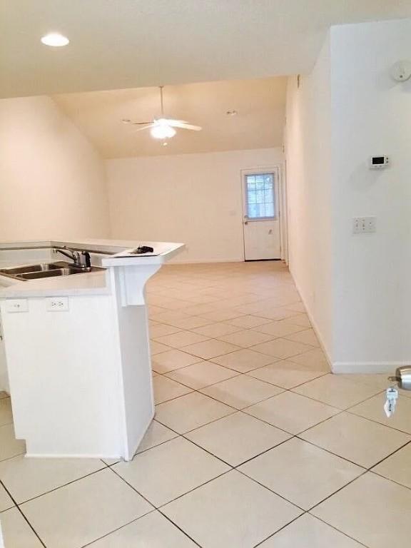 kitchen featuring white cabinets, light tile patterned floors, ceiling fan, and sink