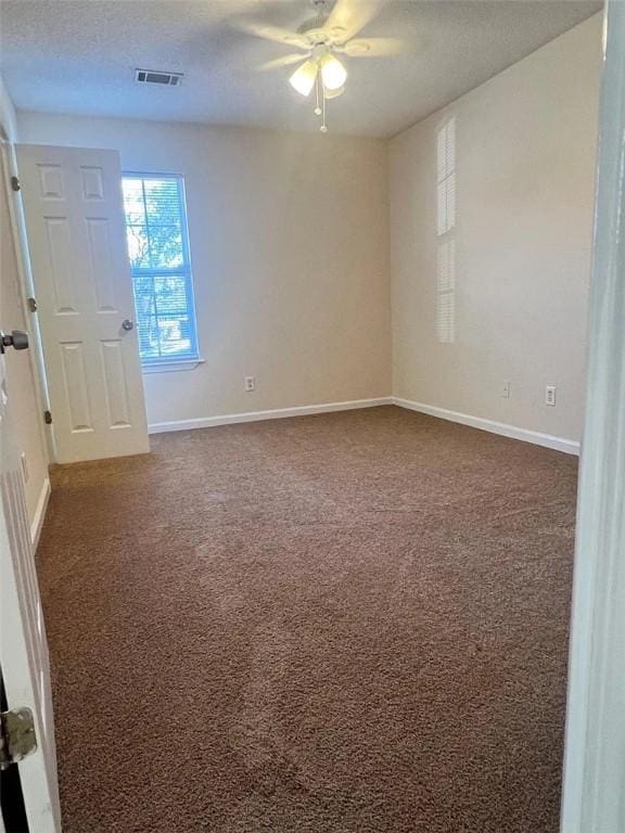 unfurnished room with ceiling fan and dark colored carpet