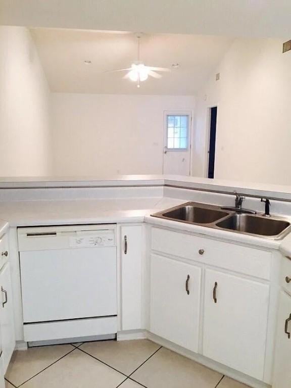 kitchen featuring white dishwasher, white cabinets, light tile patterned floors, and sink